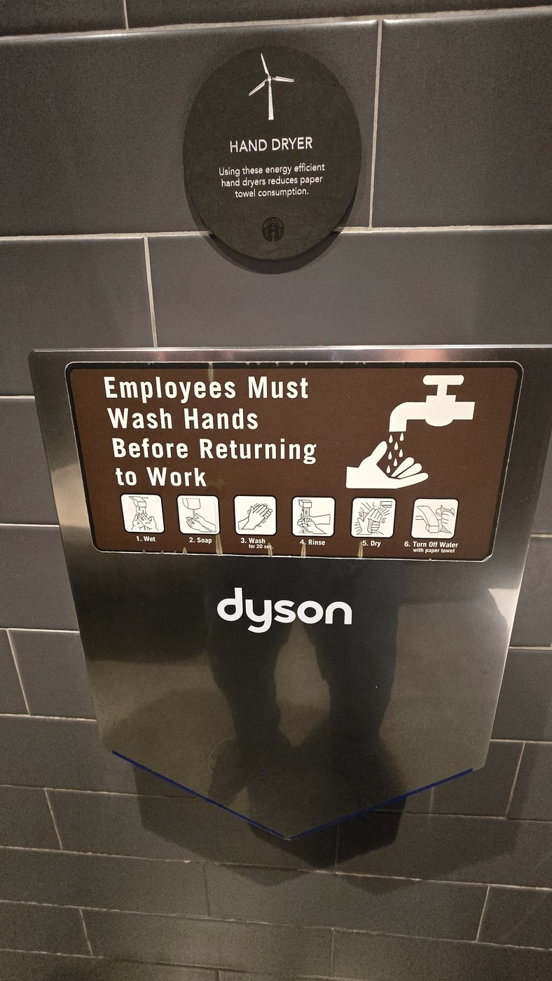 Energy-efficiency sign above a dryer; hand-washing mandate on it