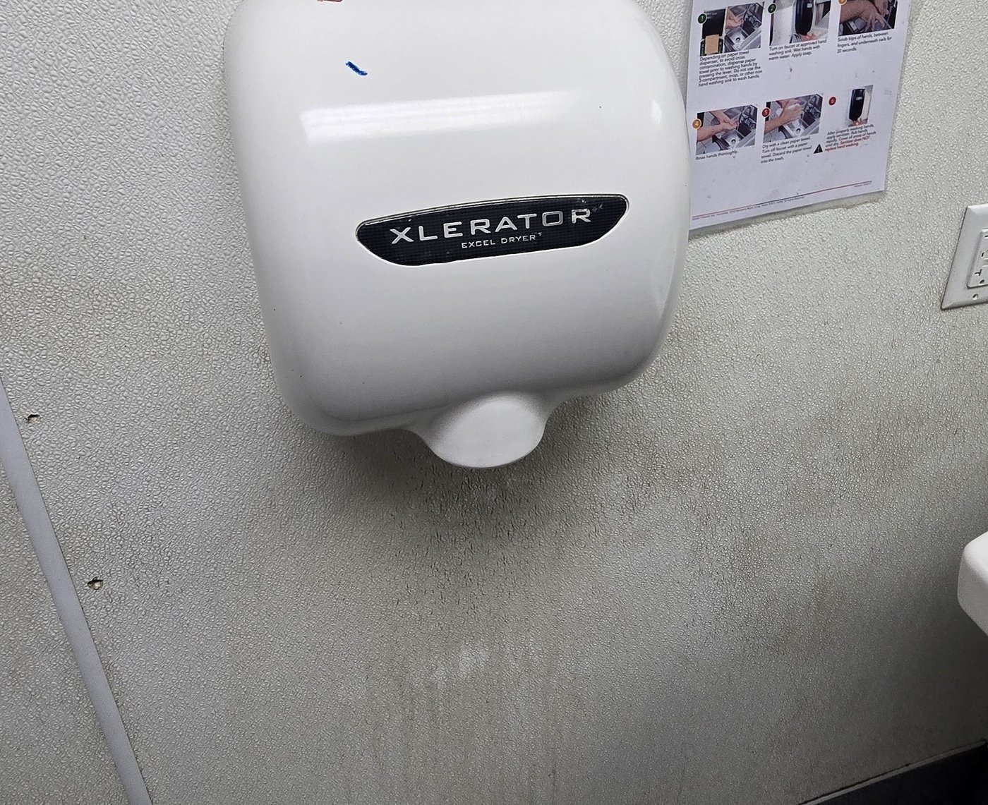 A dryer beside a posted handwashing sign